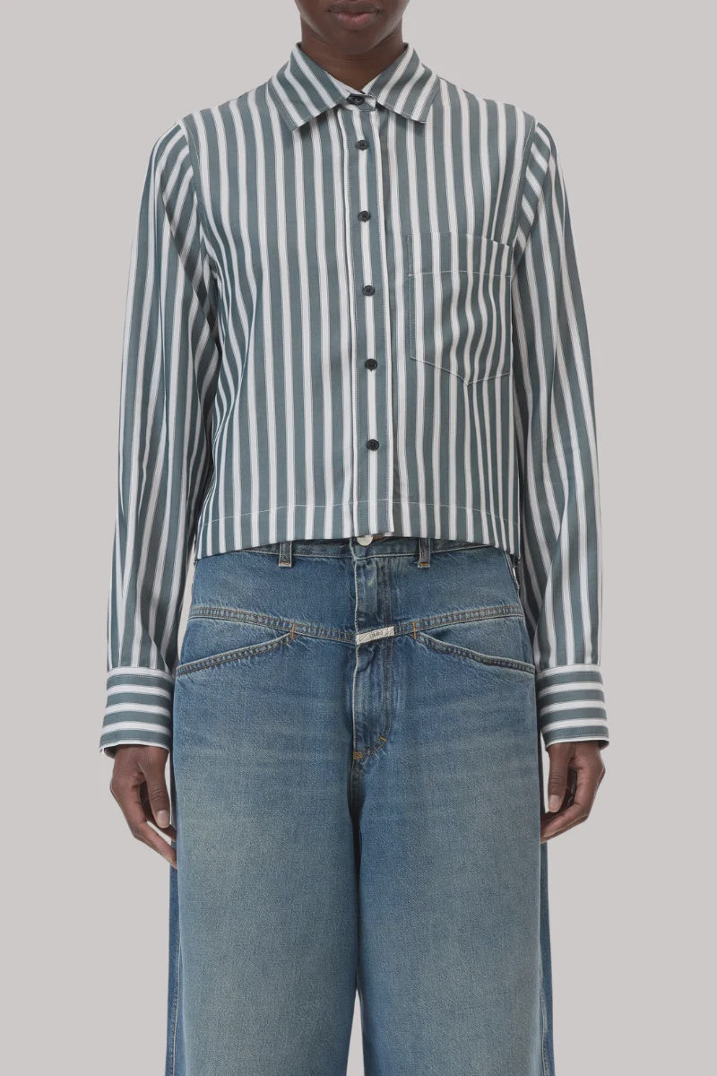A person wears the CLOSED Cropped Classic Shirt—a tailored women’s piece with stripes, collar, and chest pocket—paired with high-waisted, loose-fitting blue jeans featuring overlapping waistbands.