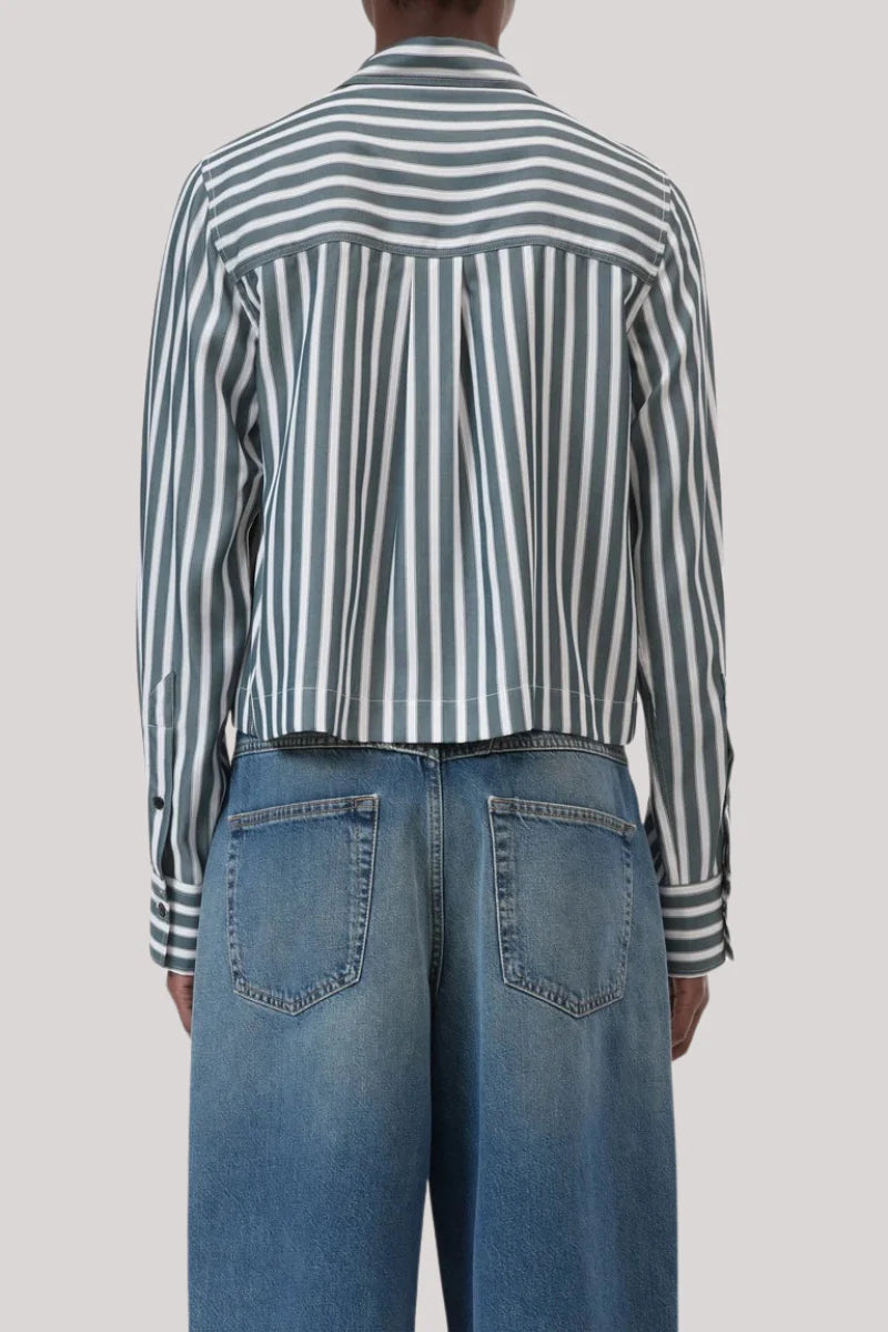 A person is shown from the back against a plain light grey background wearing CLOSED's Cropped Classic Shirt in green and white vertical stripes with blue high-waisted jeans.