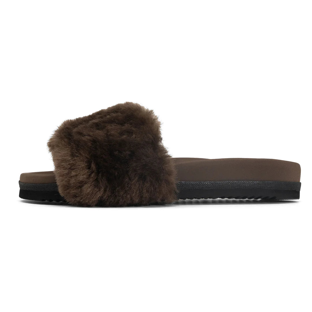 The Roam Cloud Shearling Slider is a brown sandal with a thick plush strap, black sole, and memory foam footbed, shown in profile on a white background.