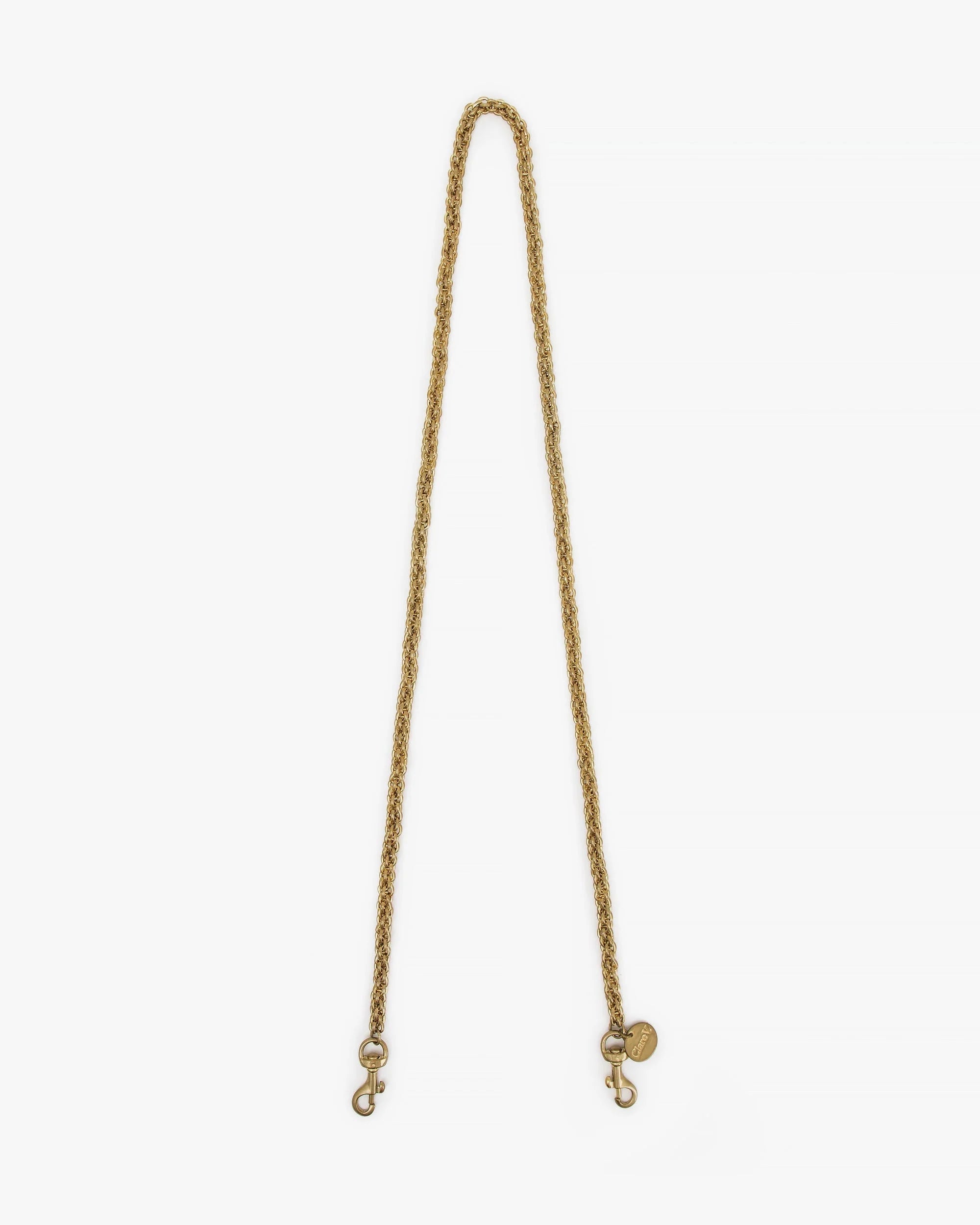 The Clare Vivier Crossbody Strap S25 features a gold rope-chain design with metal clips and a round tag, shown on a white background—ideal for adding stylish flair to your favorite bag.