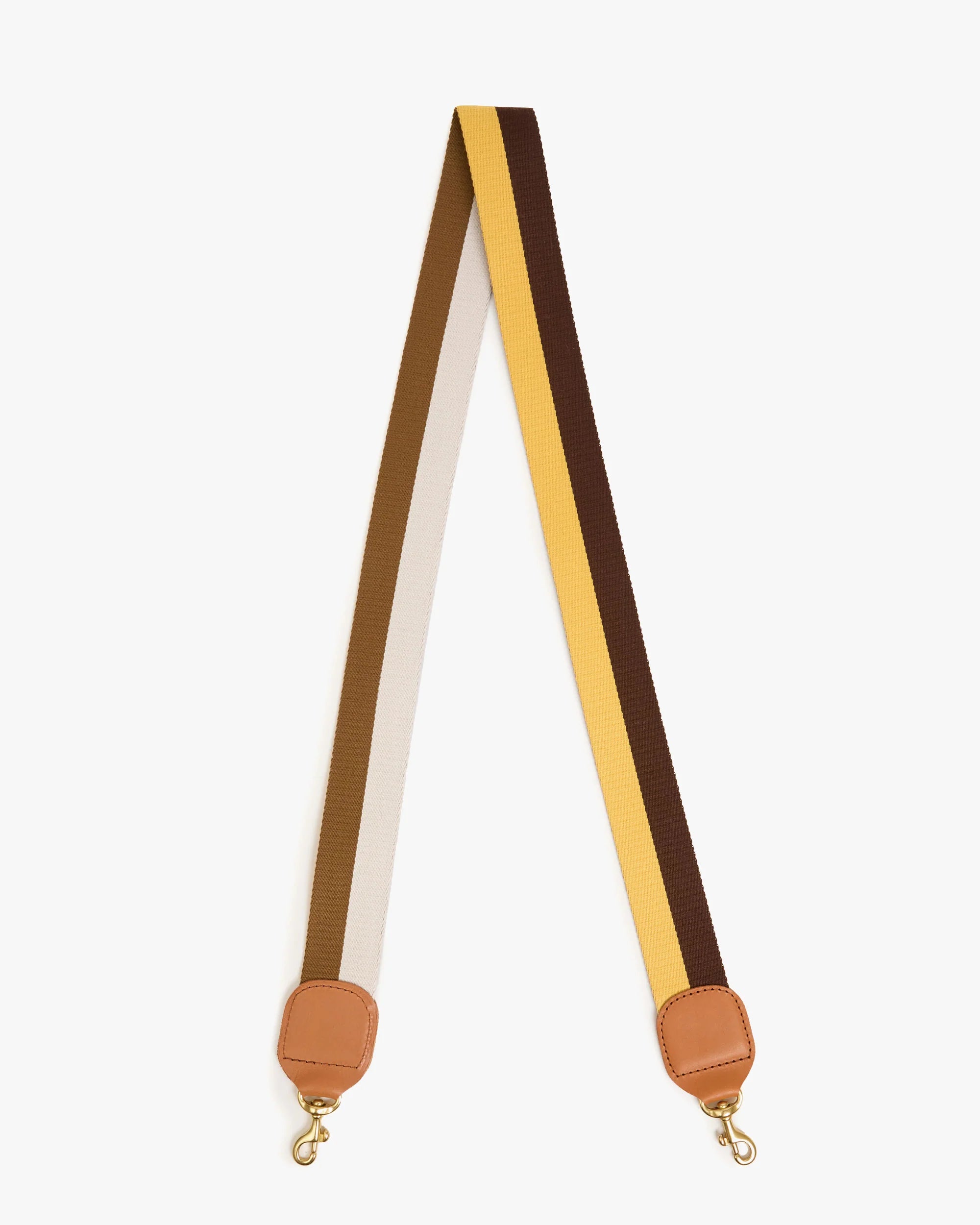 The Clare Vivier Adjustable Crossbody Strap features a cotton webbing with beige, brown, and yellow stripes, tan leather ends, and gold metal clasps.
