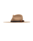 Introducing the Fenix Wool Fedora by Ninakuru, a classic wide-brimmed hat in a light brown hue. Crafted from vegan leather, it features a striking dark brown band adorned with an elegant decorative knot detail. The smooth texture and timeless design of this fedora are beautifully showcased on a plain white background.