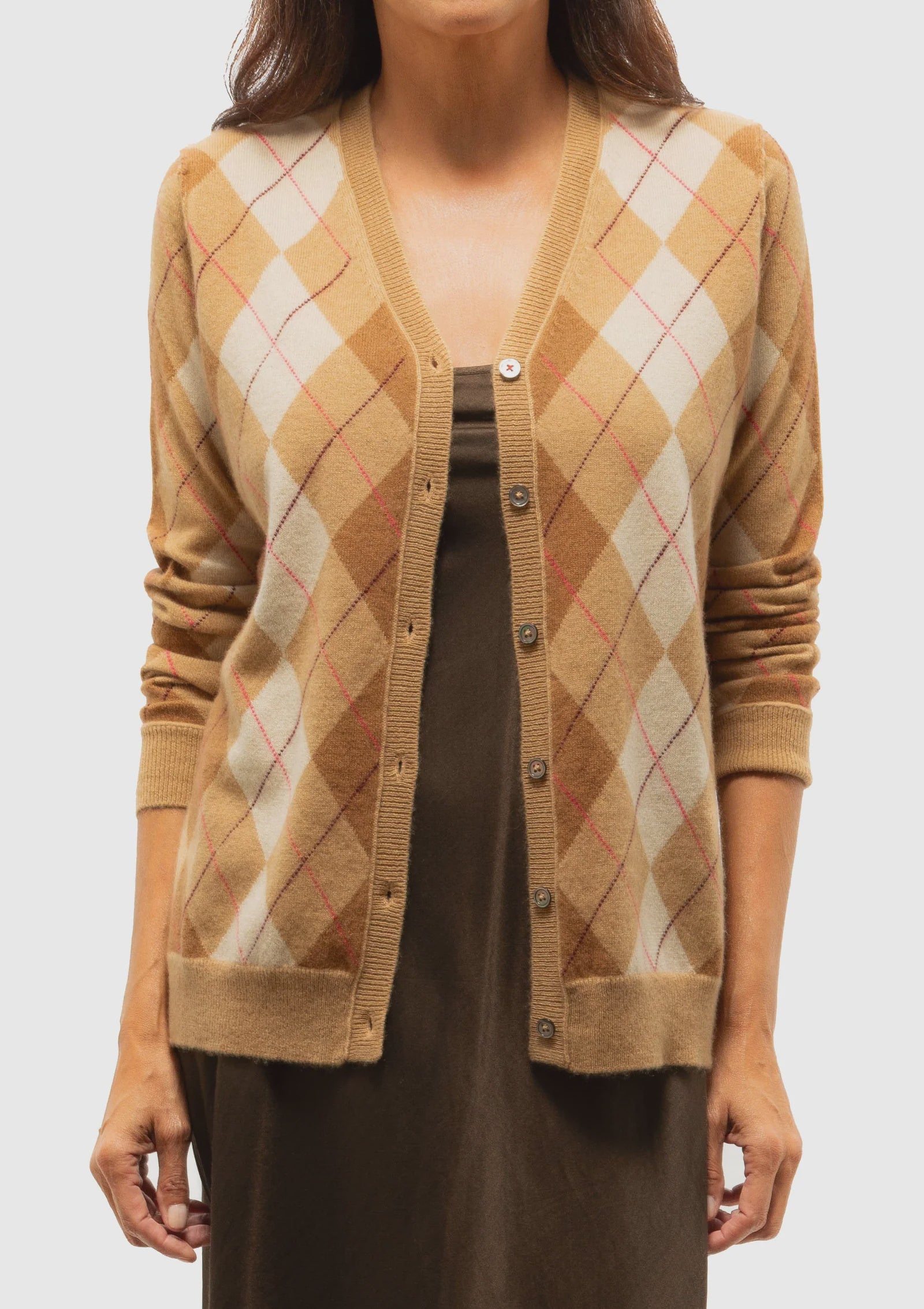 A woman models the Brazeau Tricot Argyle Cardigan in tan and brown with a button-down front, layered over a brown dress, shown from shoulders to hips against a plain background.