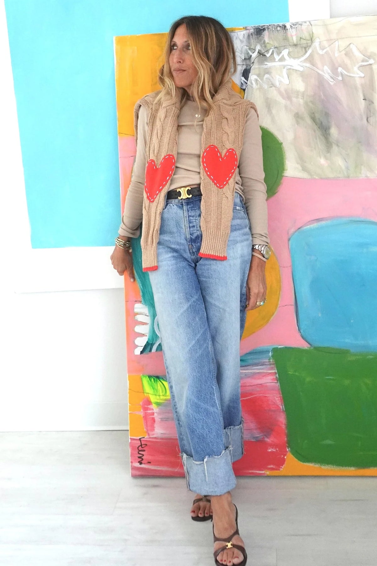 Kerri Rosenthal Maxwork Cable Sweater in cream, styled casually before a colorful abstract artwork.