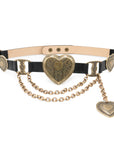 The Brass XL Heart Belt by Streets Ahead Inc, handcrafted in Los Angeles with Italian brass hardware, features ornate gold heart-shaped buckles, decorative engravings, draped gold chains, and a dangling heart charm for an elegant statement.