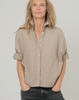Monday12 Daria Shirt in Army Beige styled with black jeans, modeled with hands in pockets facing camera.
