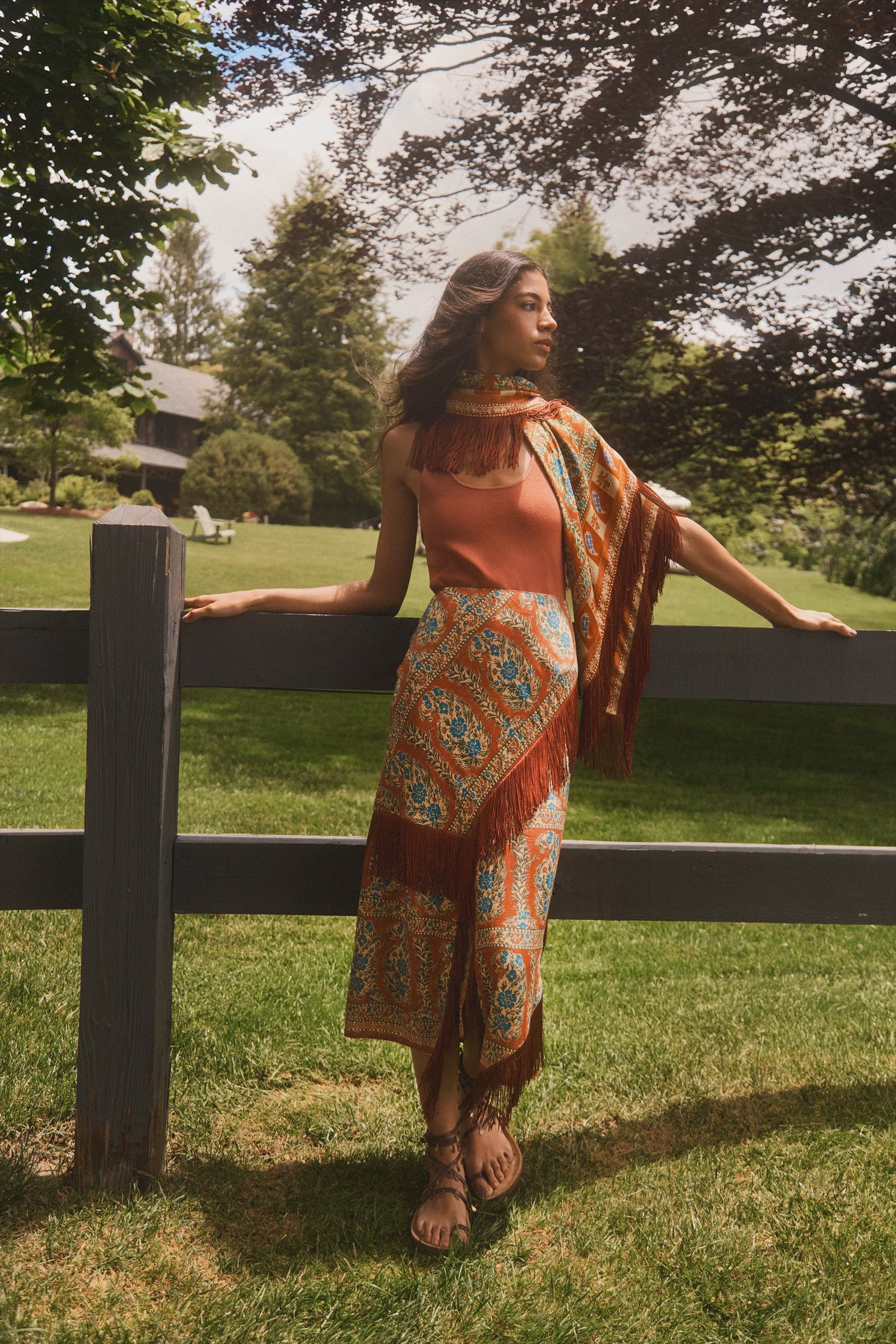 Hunter Bell NYC Allyne Skirt in a sunlit yard, styled casually by a wooden fence for a relaxed outdoor look.