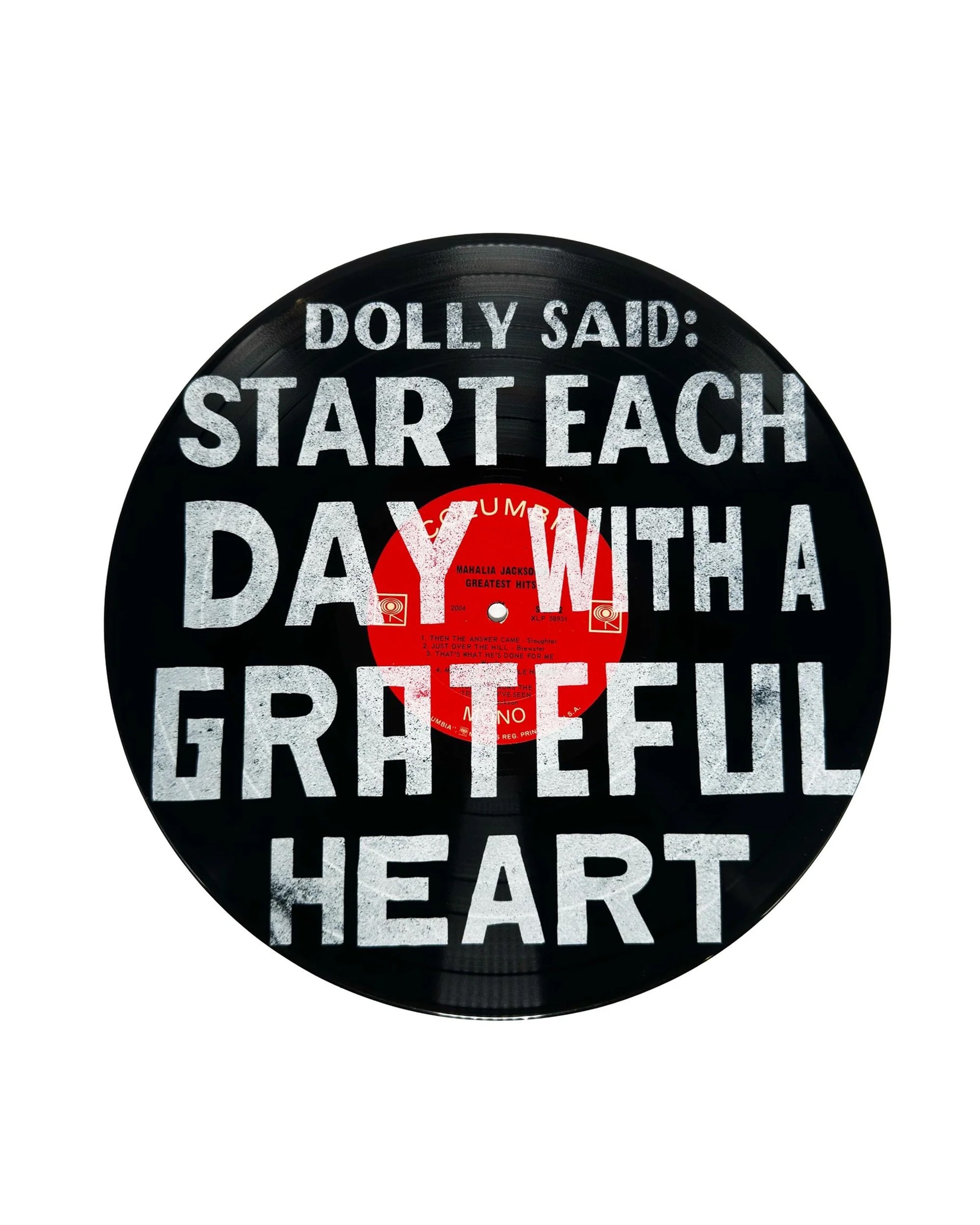 The Dolly Said Vinyl Record by Sugarboo Designs features bold white text on a red label—“Start each day with a grateful heart”—making it a striking wall decor piece for music lovers.