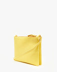 The "Double Sac Bretelle" by Clare Vivier is a sleek, rectangular yellow crossbody bag crafted from Italian leather and boasts a minimalist design. It features a zip closure at the top and comes with a slim, detachable shoulder strap attached by gold hardware. The bag is photographed standing upright against a plain white background.