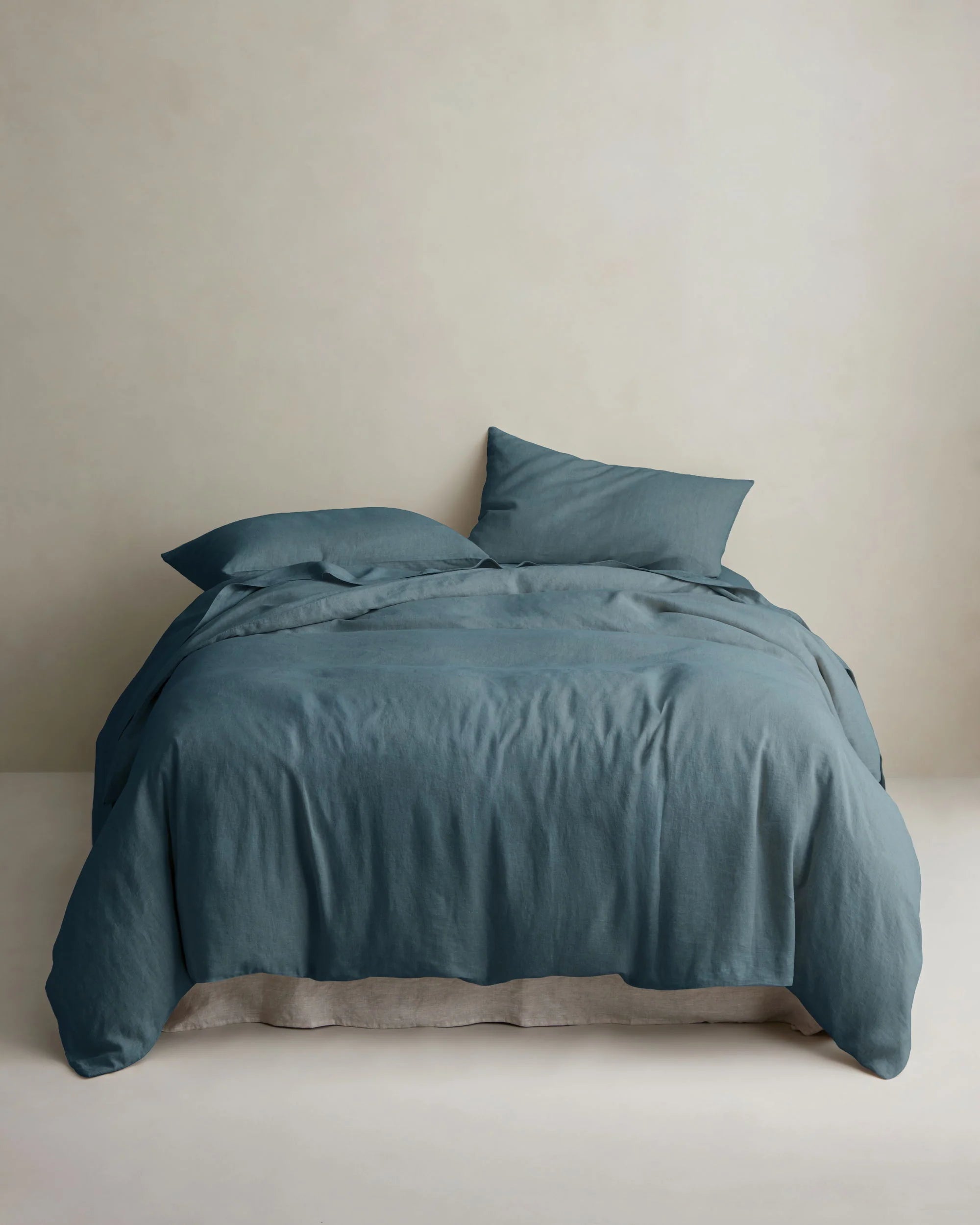 Teal linen duvet cover and pillows by Cultiver Goods on bed, set against a light wall in a serene bedroom setting.