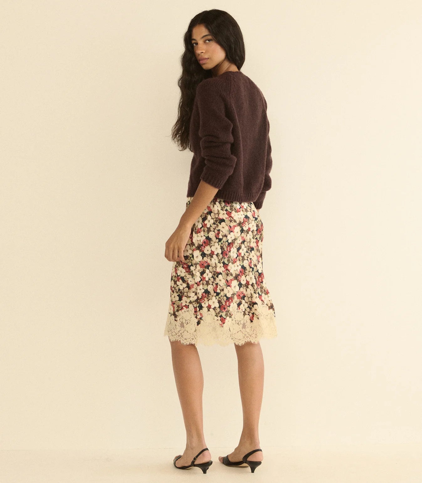 DOEN Elowette Skirt in silk satin with floral lace trim, styled with a dark sweater, shown in a modern interior.