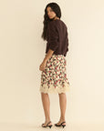 DOEN Elowette Skirt in silk satin with floral lace trim, styled with a dark sweater, shown in a modern interior.
