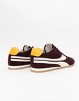 The ONCEPT Essex Sneaker, crafted from ultra-lightweight maroon Italian suede with white accents and yellow heel tabs, is shown on a white background from the back and side views.