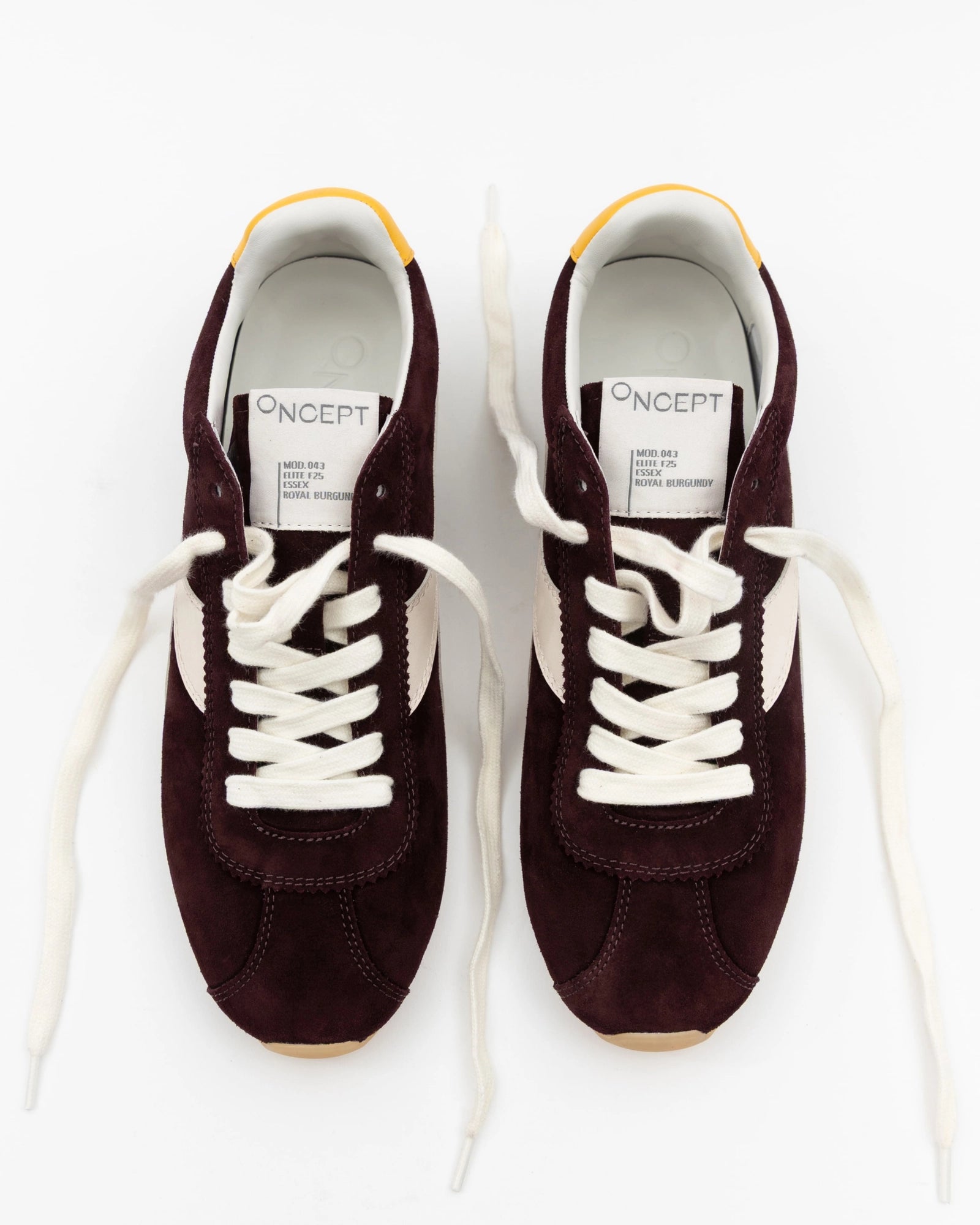 A pair of Essex Sneakers by ONCEPT, crafted from burgundy Italian suede with white laces, side panels, and yellow-accented heel tabs, are displayed side by side on a white background. The insoles are branded "ONCEPT.