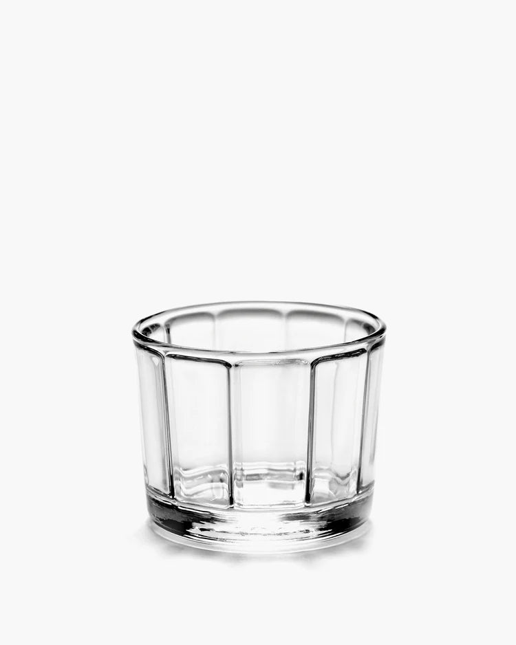 The Surface Glassware by Serax is a small, clear glass bowl with vertical ridge patterns, shown on a plain white background and reflecting contemporary designer elegance.