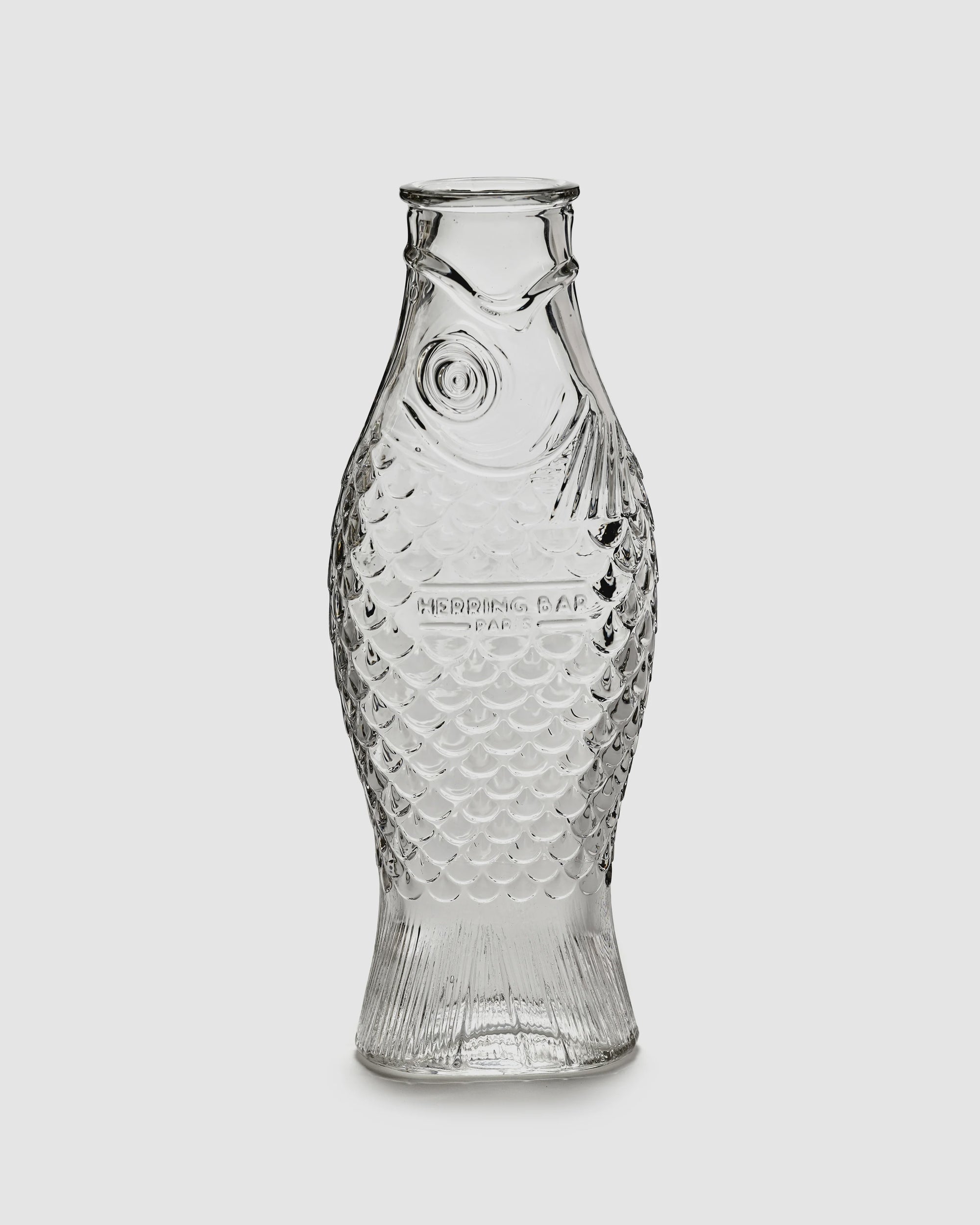 Clear glass fish-shaped carafe with scale and fin details by Serax, upright design, perfect for dining table decor.