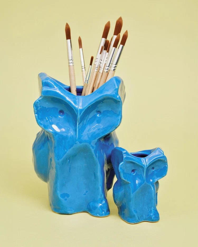Blue Serax Owl vases on a yellow surface, one used as a paintbrush holder; playful ceramic decor for Bungalow.