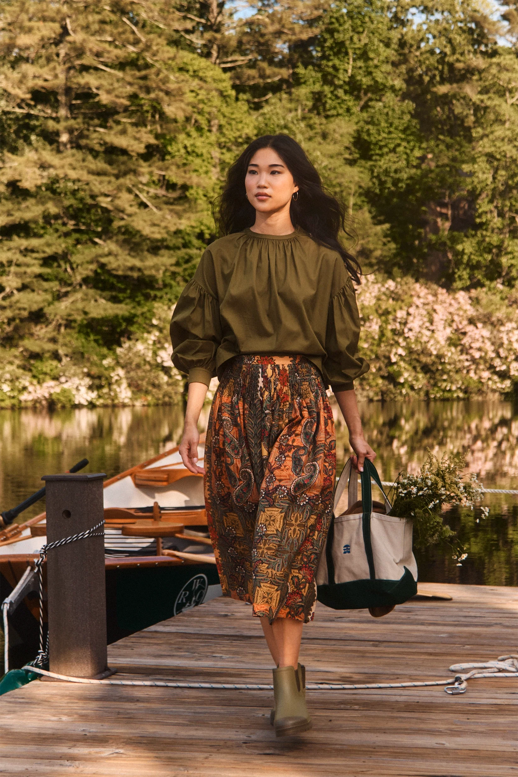 Fallon Skirt by Hunter Bell NYC styled for a lakeside stroll, paired with a casual tote on a dock with trees in view.
