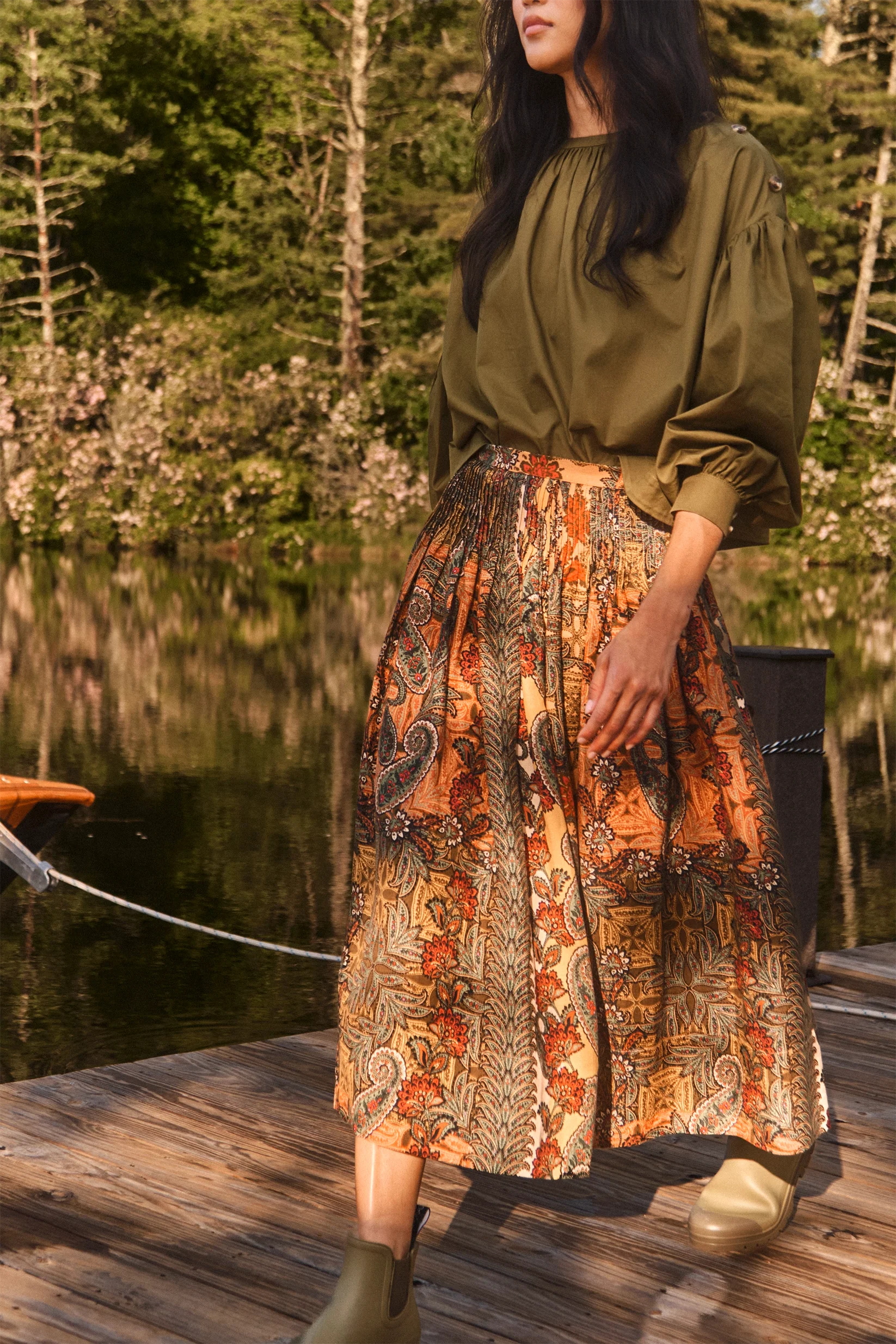 Fallon Skirt by Hunter Bell NYC styled with olive blouse and boots on a lakeside dock, natural outdoor setting.