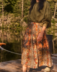Fallon Skirt by Hunter Bell NYC styled with olive blouse and boots on a lakeside dock, natural outdoor setting.