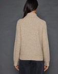 A person with long dark hair is wearing the Deep Pockets Zip sweater by Lisa Todd and dark pants, standing with their back to the camera against a gray background.