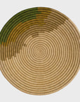 A Restorative Woven Bowl 21" Moss featuring concentric circles in various shades of green and beige, isolated on a white background, perfect for a Scottsdale Arizona bungalow.