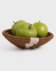 Three fresh green apples in a small brown Woven Bowl 6" by Kazi Goods against a white background in a Scottsdale, Arizona Bungalow.