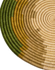 Circular woven mat featuring concentric circles in shades of beige and green, with a gradual transition in colors from the center to the perimeter, perfect for a Scottsdale Arizona bungalow by Kazi Goods.