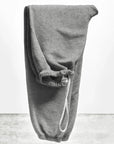 A pair of BASIC GOODNESS OG SWEATPANTS by Free City (sparrow, LLC) in gray French terry with an elastic waistband and white drawstring, neatly folded upright on a light gray textured surface against a plain white background.