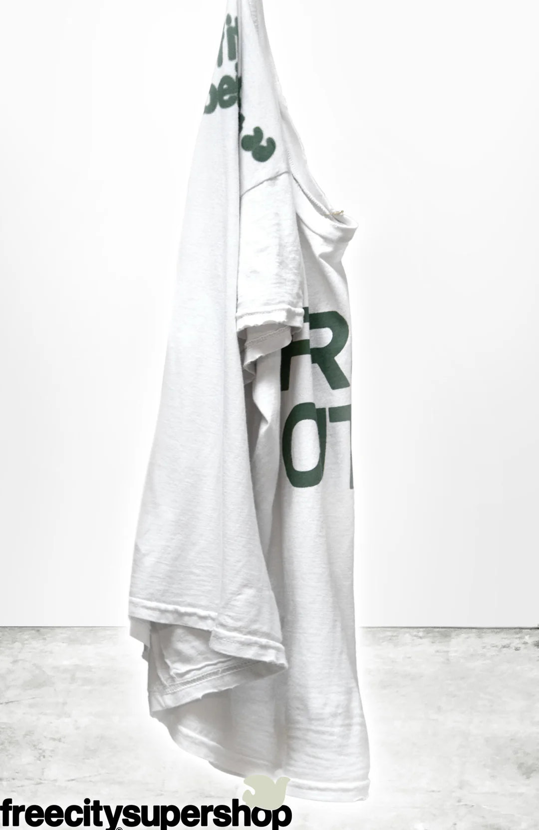 A unisex, white hand-screen printed t-shirt from Free City (sparrow, LLC), featuring green "thedoingofitisthebeingofit" text, is displayed on a plain background. "freecitysupershop" appears in bold black letters at the bottom.