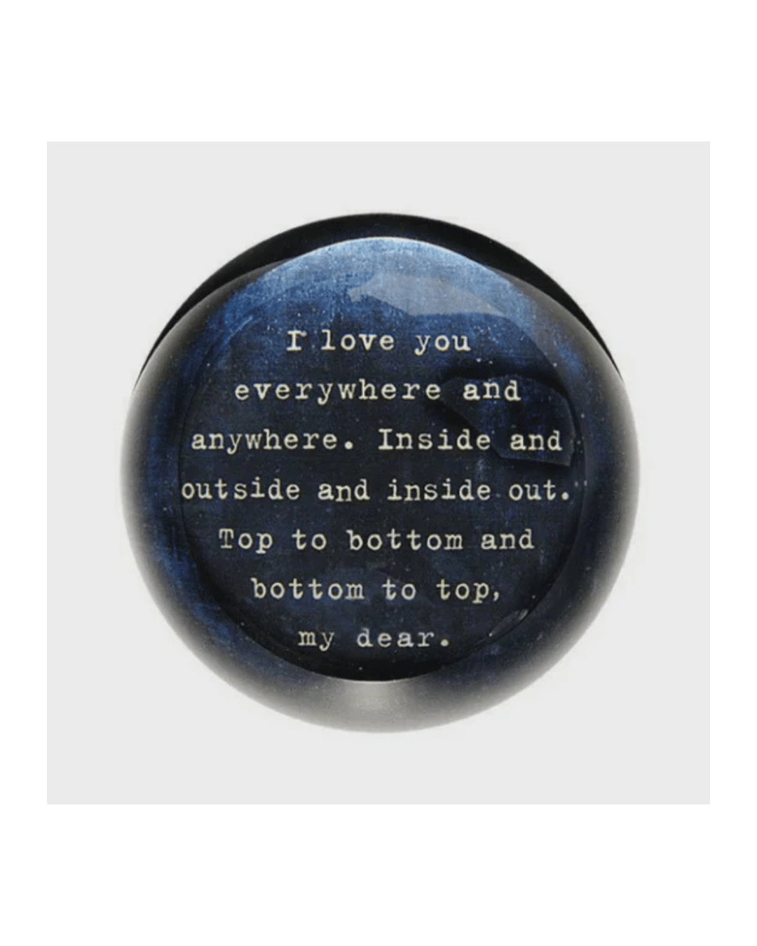 The Paperweight I Love You Everywhere by Sugarboo Designs is a round paperweight with a dark blue surface, featuring Rebecca Puig's bedtime mantra in elegant white text: "I love you everywhere and anywhere. Inside and outside and inside out. Top to bottom and bottom to top, my dear.