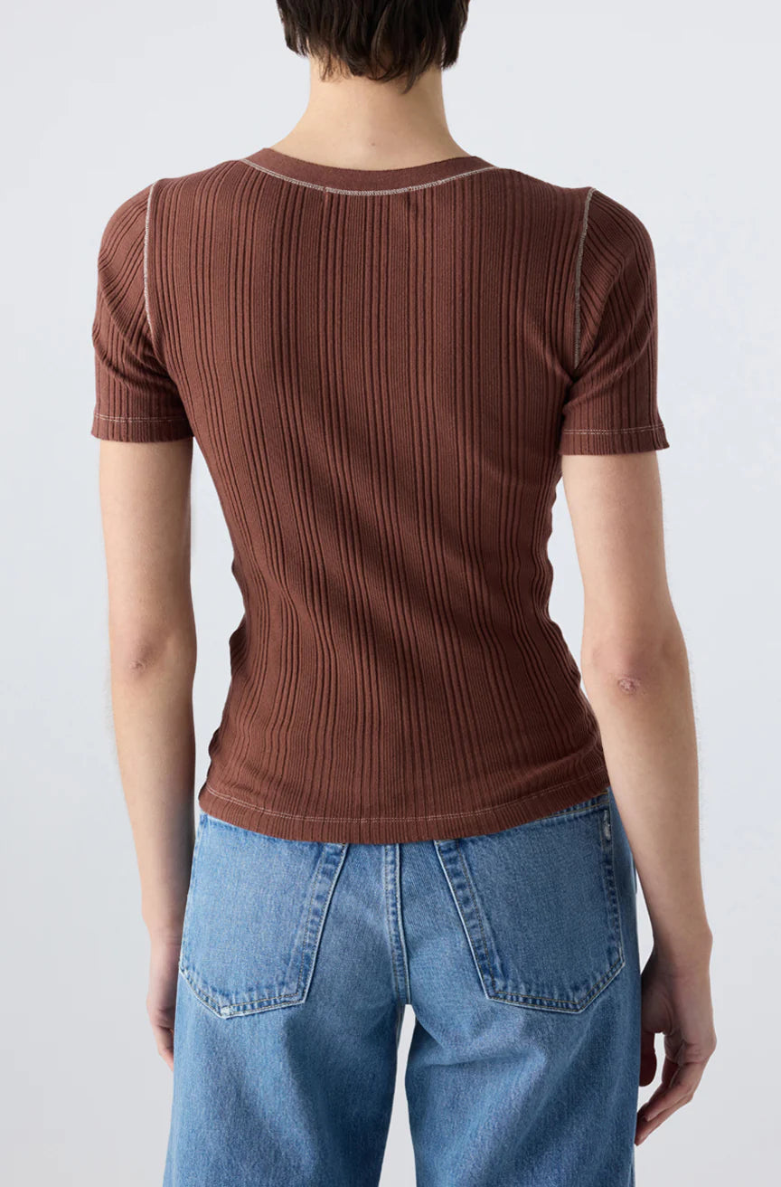 Seen from behind, a person with short hair wears the Cherish Tee by AMO Denim—a ribbed cotton top with a fitted silhouette—paired with blue jeans, set against a plain light background.