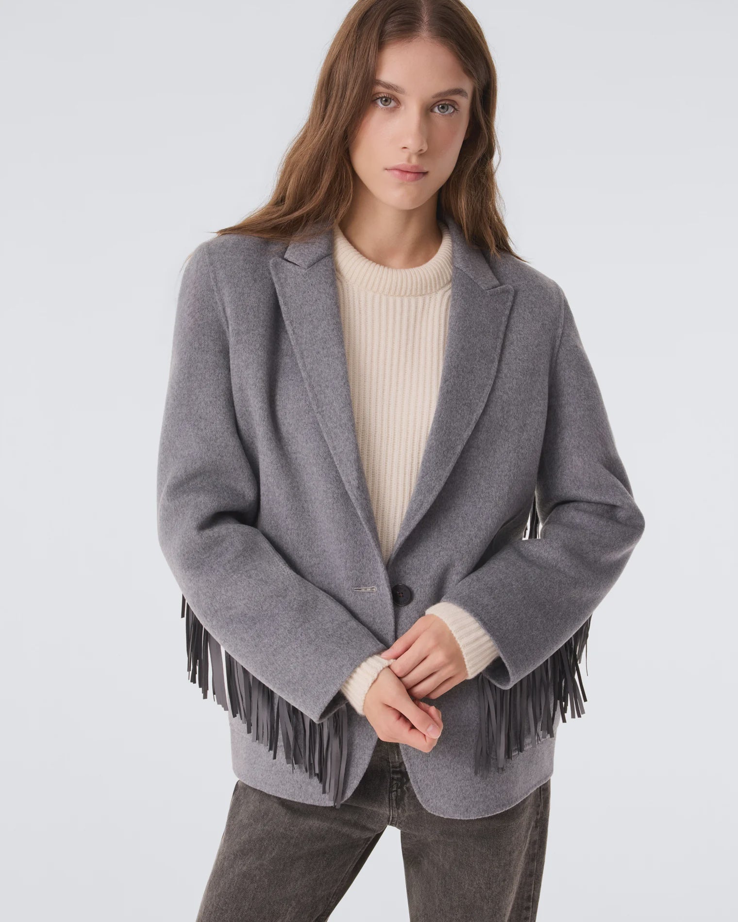 KUJTEN G3 fringe blazer over cream sweater and dark jeans, styled against a neutral background.