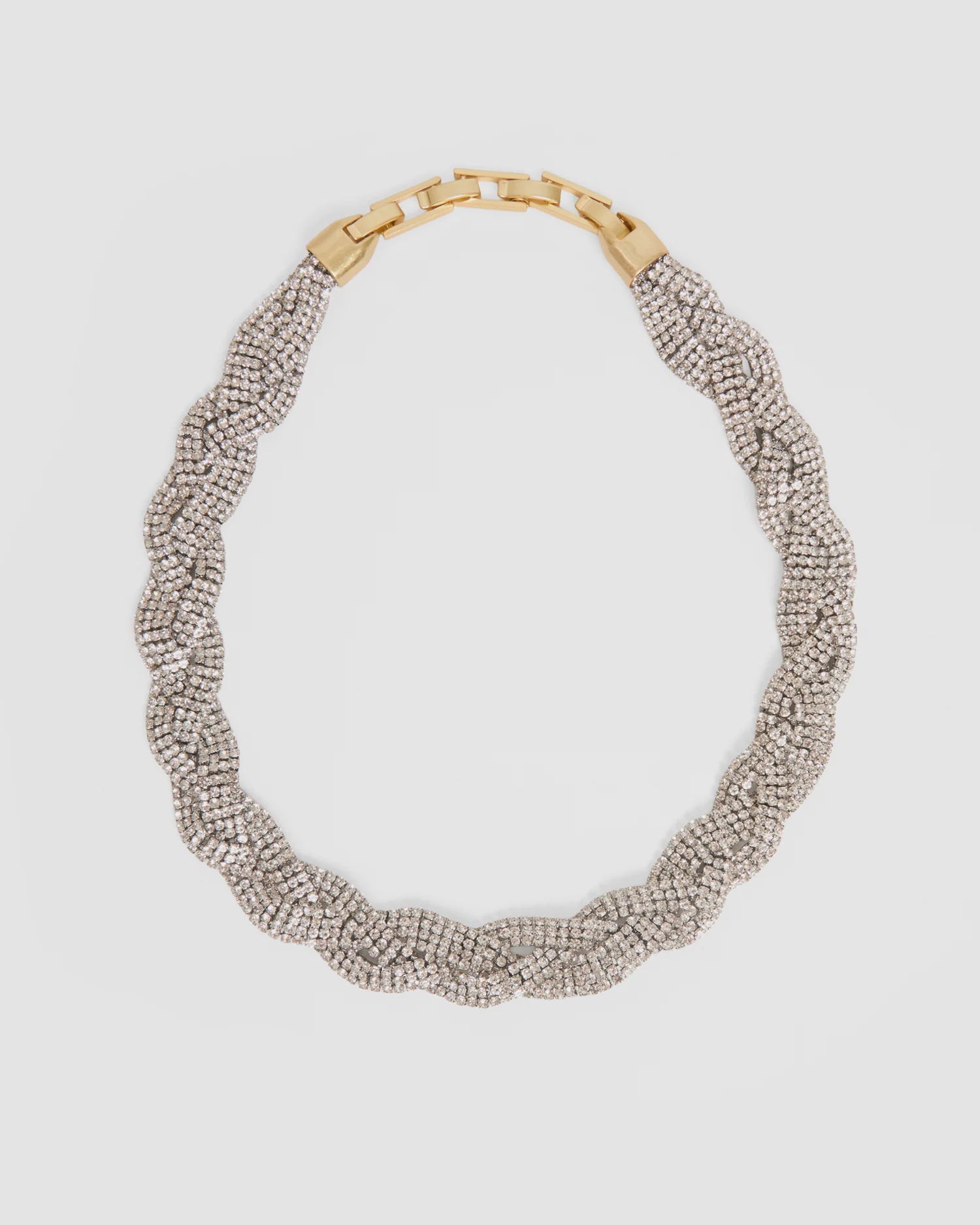 The Fete Collar by Clare Vivier is a braided necklace with rows of sparkling pavé glass stones and a vintage gold-plated brass foldover clasp, shown on a plain white background.