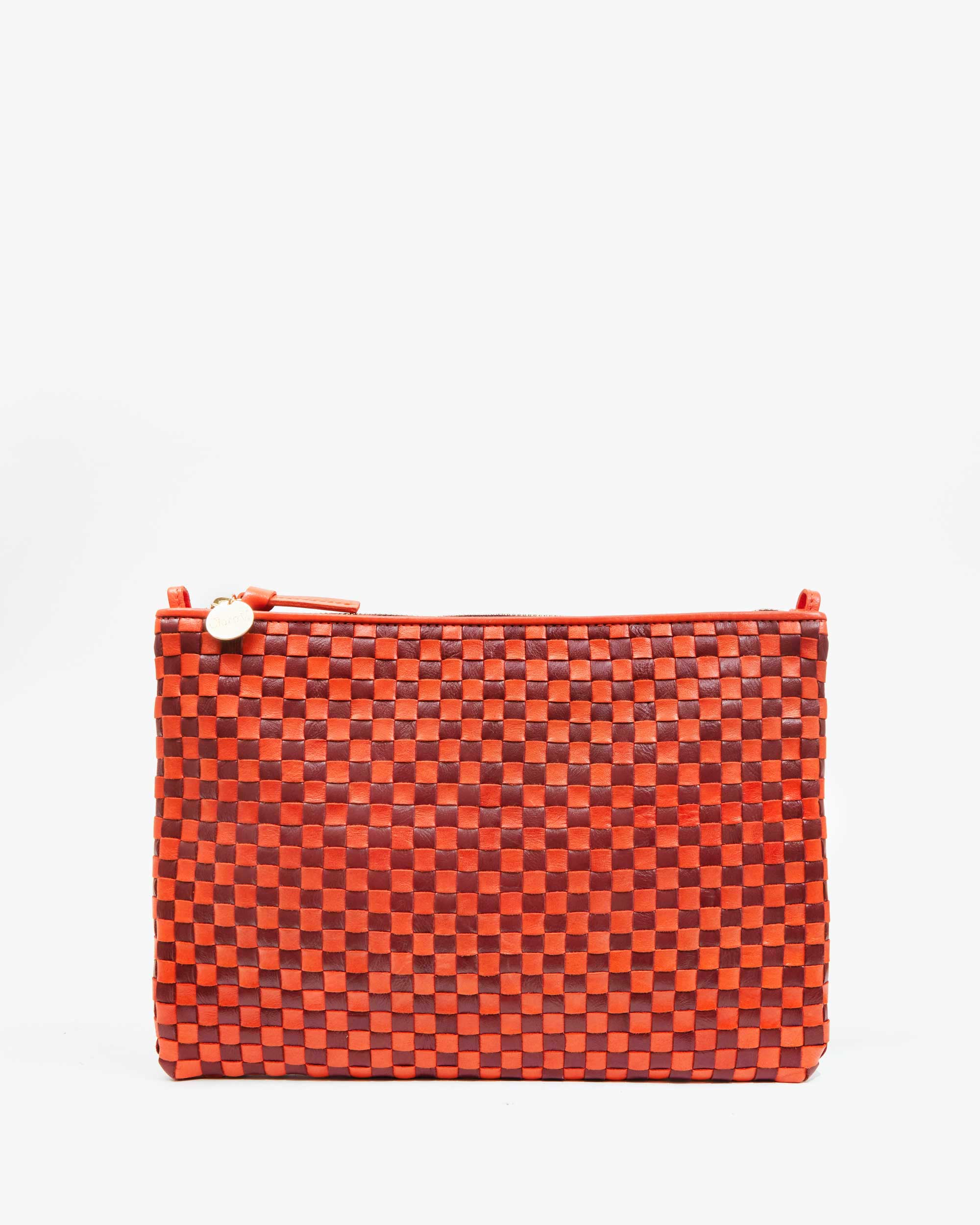 Clare Vivier's "Flat Clutch w/ Tabs" is shown against a plain white background. The red, handwoven leather clutch bag features a checkered pattern and a top zipper with a round pull, combining style and functionality seamlessly.