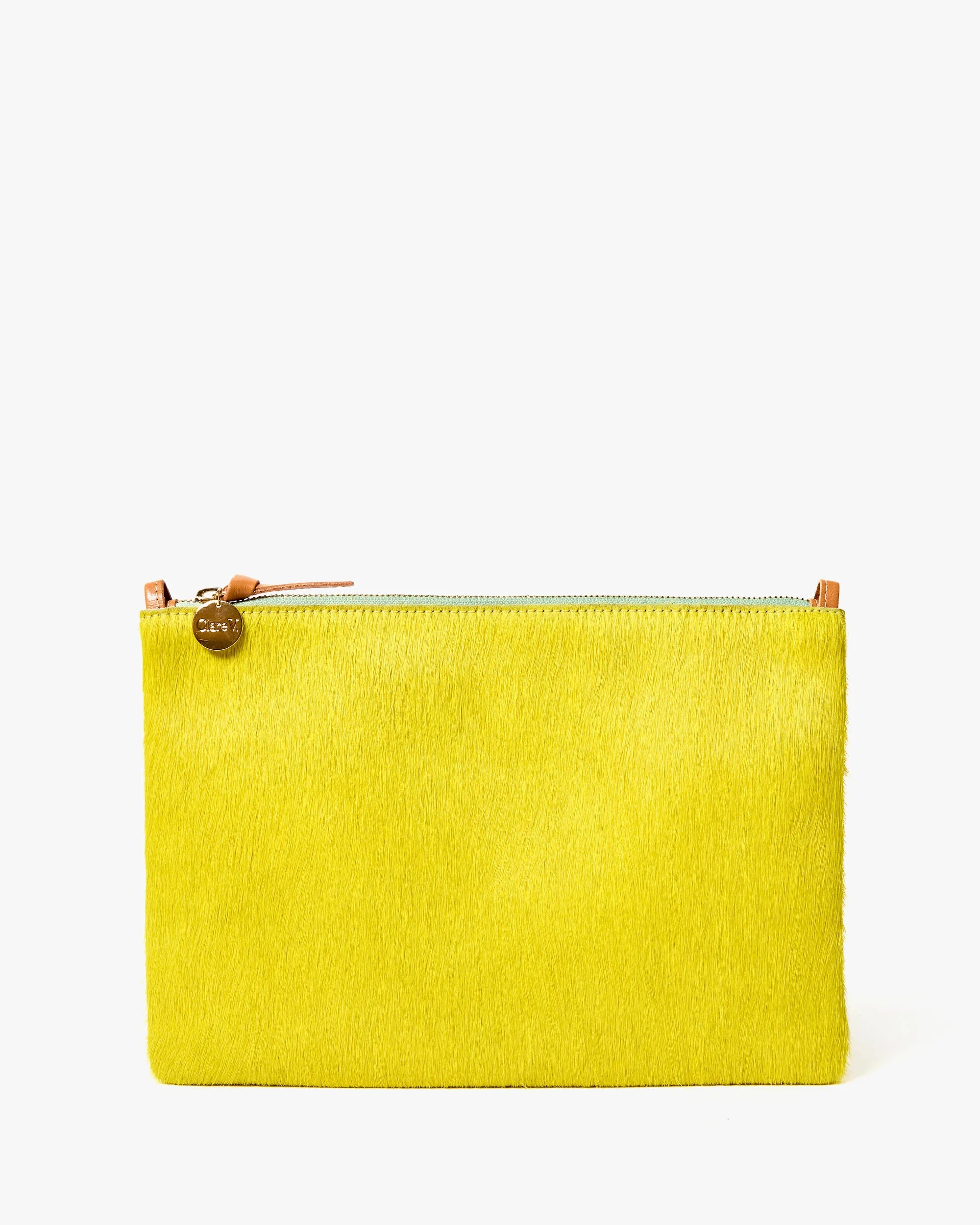 The Clare Vivier Flat Clutch W/ Tabs S25 is a rectangular yellow bag with a crocheted cotton surface, silver zipper, tan leather pull, and a round gold charm, shown against a plain white background.