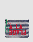 The La Plage Flat Clutch w/tabs by Clare Vivier features navy and white horizontal stripes, bold upside-down red “PLACE” lettering with geometric shapes, and a green sail cord wristlet on the zipper.
