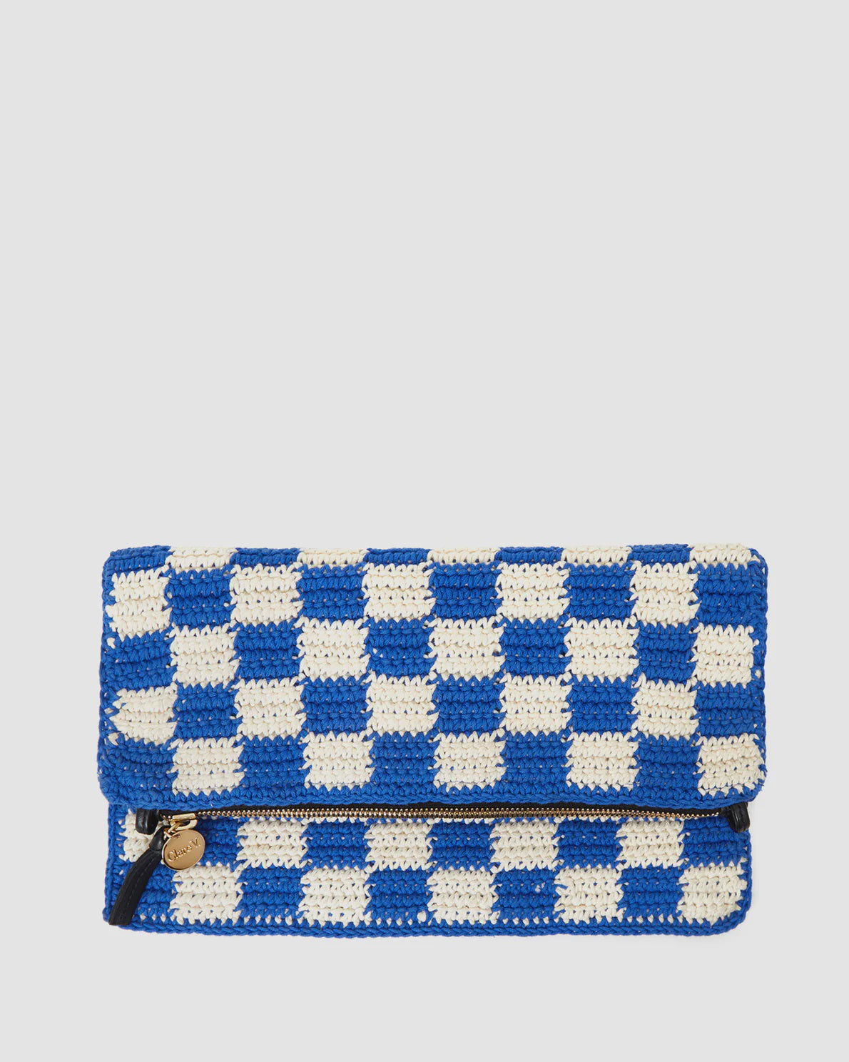 A Clare Vivier Foldover Clutch w/Tabs featuring a blue and white checkered pattern. The bag has a flap closure and a visible zipper pocket on the front adorned with a small gold-colored charm. The background is plain white.