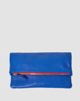 The Foldover Clutch W/ Tabs 26 by Clare Vivier features blue Italian nappa leather, a fold-over design, and a red front zipper, all displayed against a plain white background.