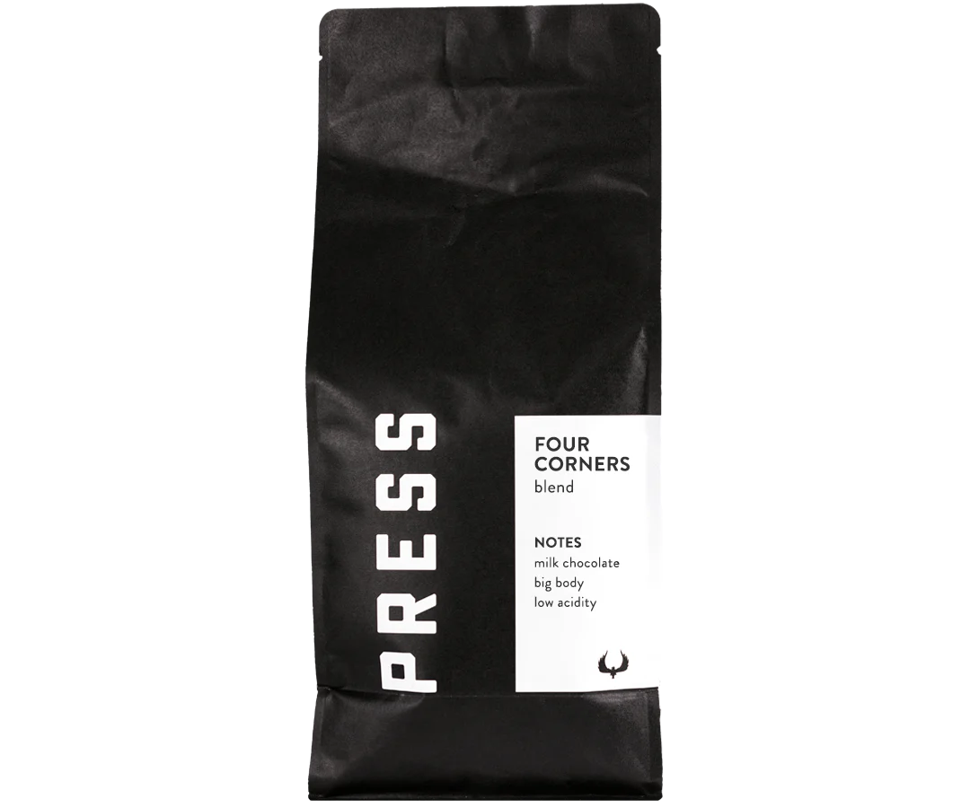 A black bag of Jeff's Antiques Press Coffee 5lb, labeled "Four Corners blend," features tasting notes of milk chocolate, big body, and low acidity on a white section of the packaging.