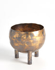 The Alchemy Container Burnt Brass S by Global Views is a round, hammered metallic vessel in golden-bronze, standing on three cylindrical legs against a plain white background.