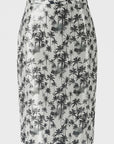 The Black Palms Pencil Skirt by Le Superbe is a high-waisted, knee-length piece in metallic silver with an all-over black palm tree print.