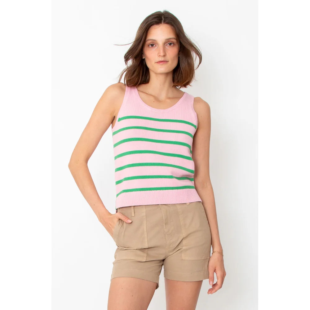 A person with shoulder-length hair wears a sleeveless pink top with green stripes and Kule's beige "The City Short" cotton shorts, made in Italy. They stand against a plain white background with one hand in their pocket.