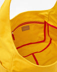 A close-up of the Grand Bando Canvas by Clare Vivier shows the yellow cotton tote’s interior, featuring a zippered pocket and red trim along the edges of its pockets.
