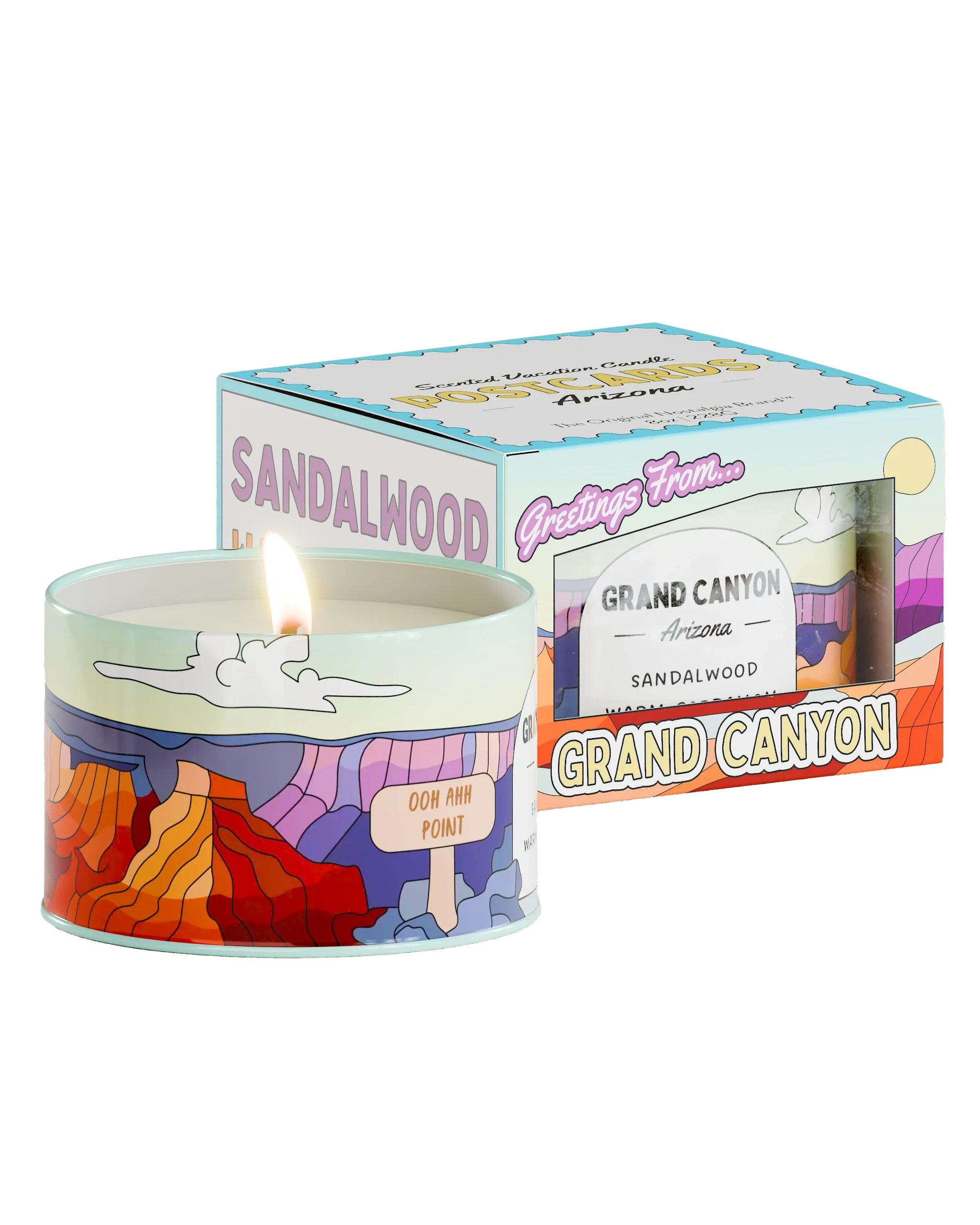 A lit sandalwood-scented Postcards Candle with colorful packaging illustrating the Grand Canyon. The circular container shows a multi-colored canyon scene and is labeled &quot;Ooh Aah Point.&quot; The box reads &quot;Greetings From... Grand Canyon, Arizona&quot; and features similar artwork reminiscent of scenic vistas found in Sedona, Arizona.