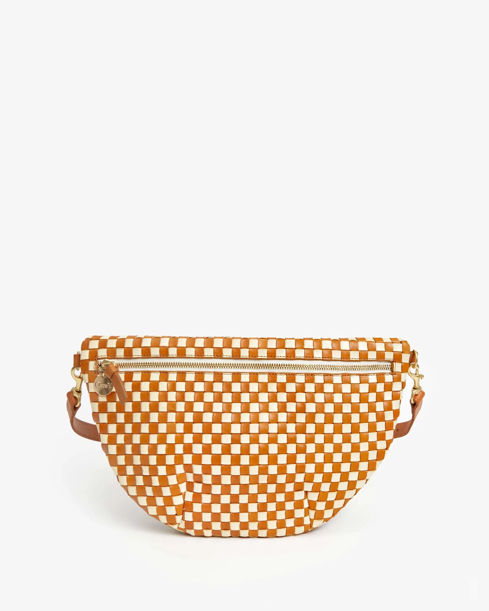 The Clare Vivier Grande Fanny Woven Checker, a checkered orange and white handbag with a zipper, is displayed on a plain white background. It comes with an adjustable strap for hands-free use, dual side handles, and elegant gold hardware.