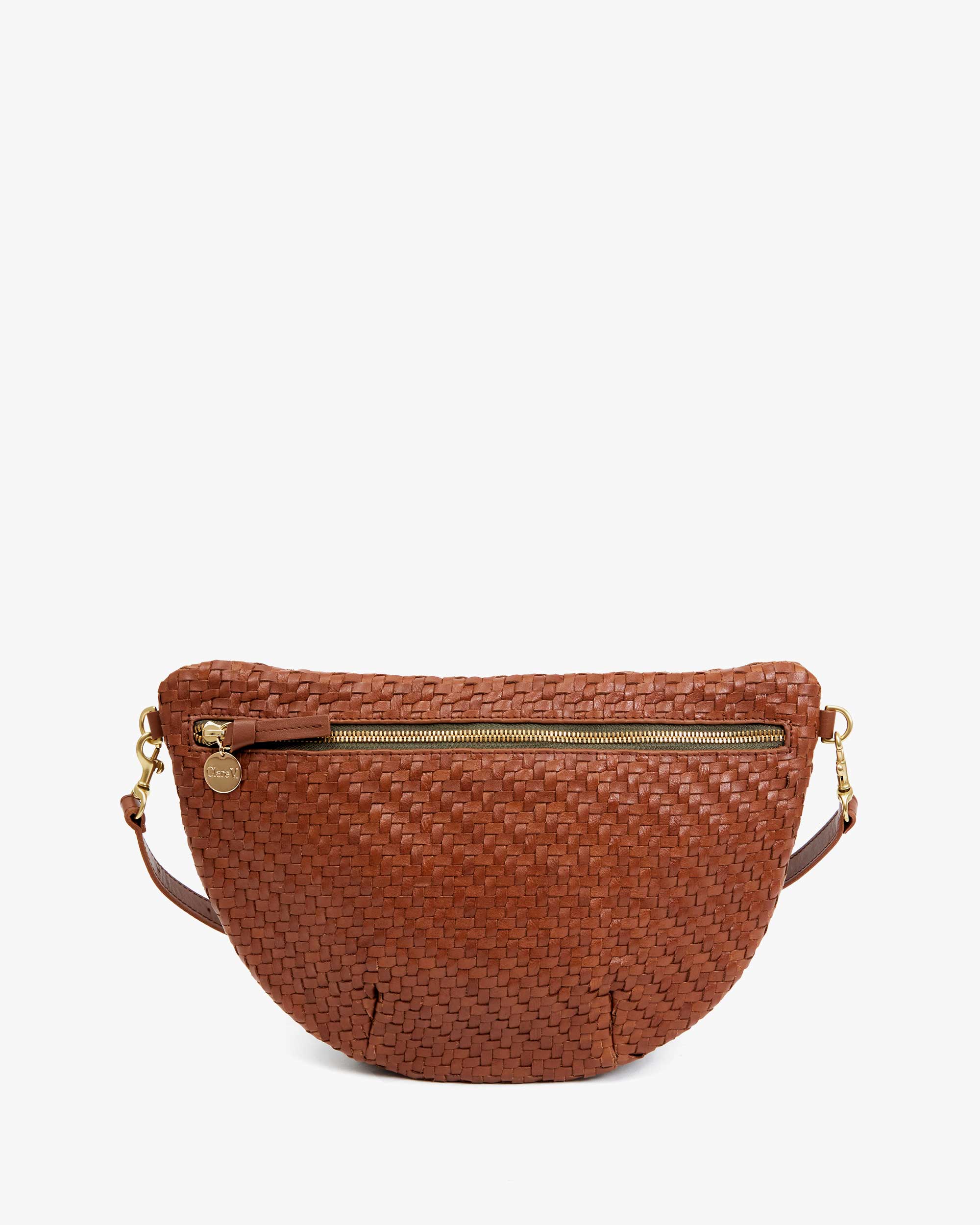 The Grande Fanny Zig-Zag by Clare Vivier is a woven brown leather shoulder bag with a curved shape. It features a top zipper closure, gold hardware, and includes a small round charm near the zipper. The bag also offers a detachable strap for crossbody wear, all set against a plain white background.