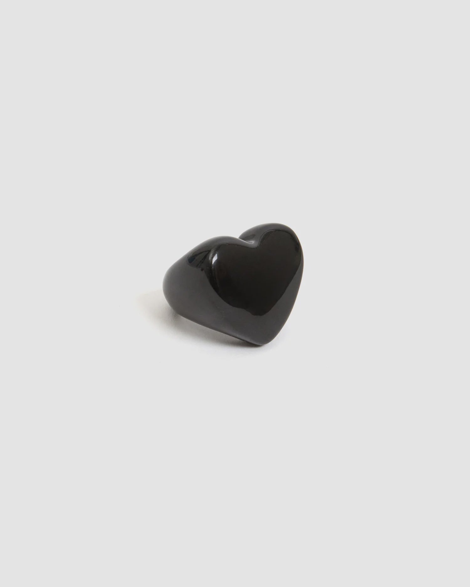 The Grande Heart Ring / Black by Clare Vivier is a glossy black resin heart-shaped ring, ideal for love jewelry fans, shown on a simple light gray background.