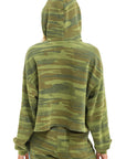 Seen from behind, a person wears the Aviator Nation 5 Stripe Cropped Pullover Hoodie Relaxed in a comfortable camouflage vintage style, hood up and arms relaxed at their sides with matching pants.