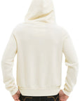 A person is seen from the back wearing an Aviator Nation 5 Stripe zip hoodie in cream, hood up, paired with dark jeans and hands on hips against a plain white background.